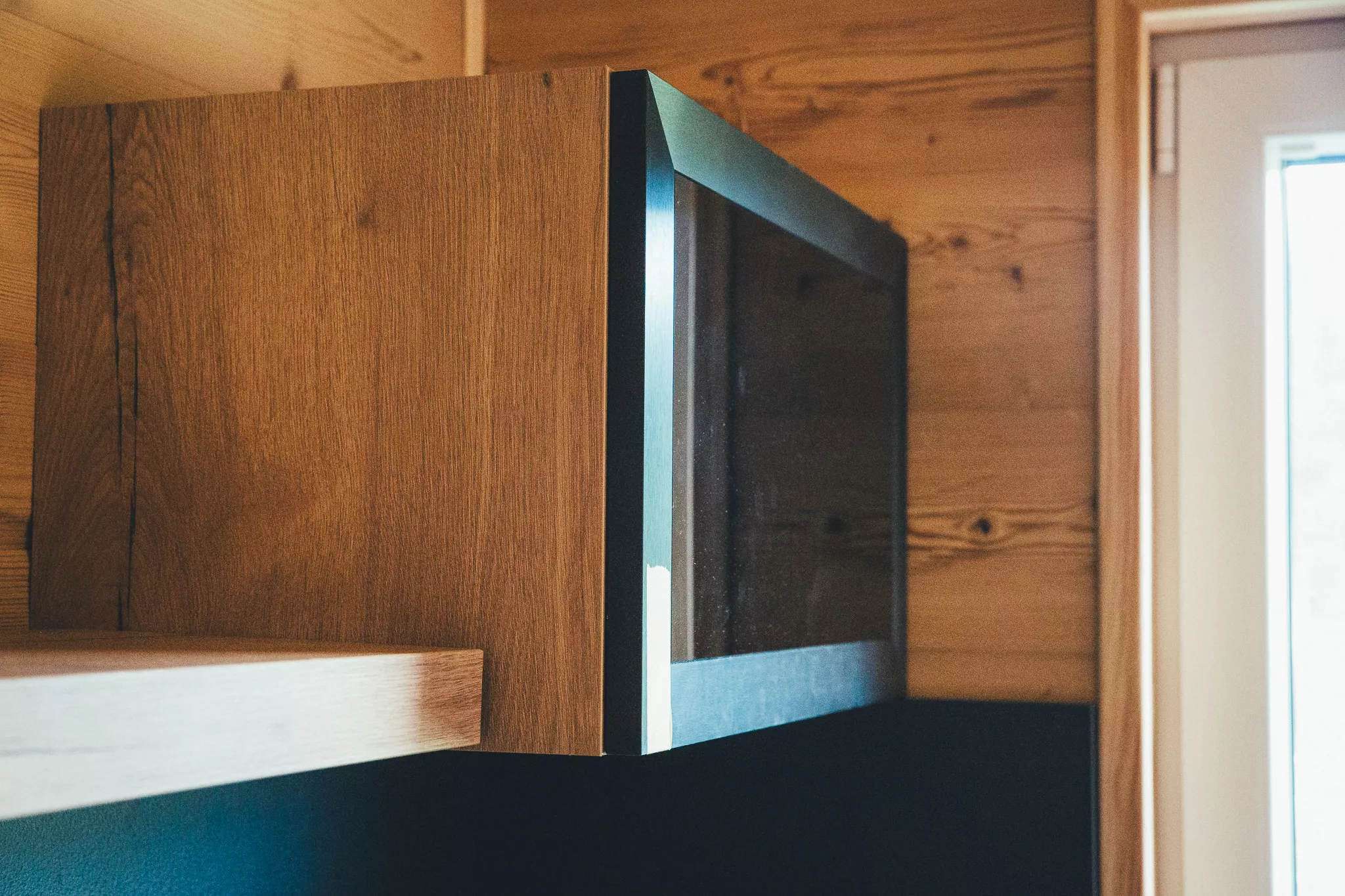 Holzverkleideter Innenraum eines Tiny Houses mit wandmontiertem Fernseher