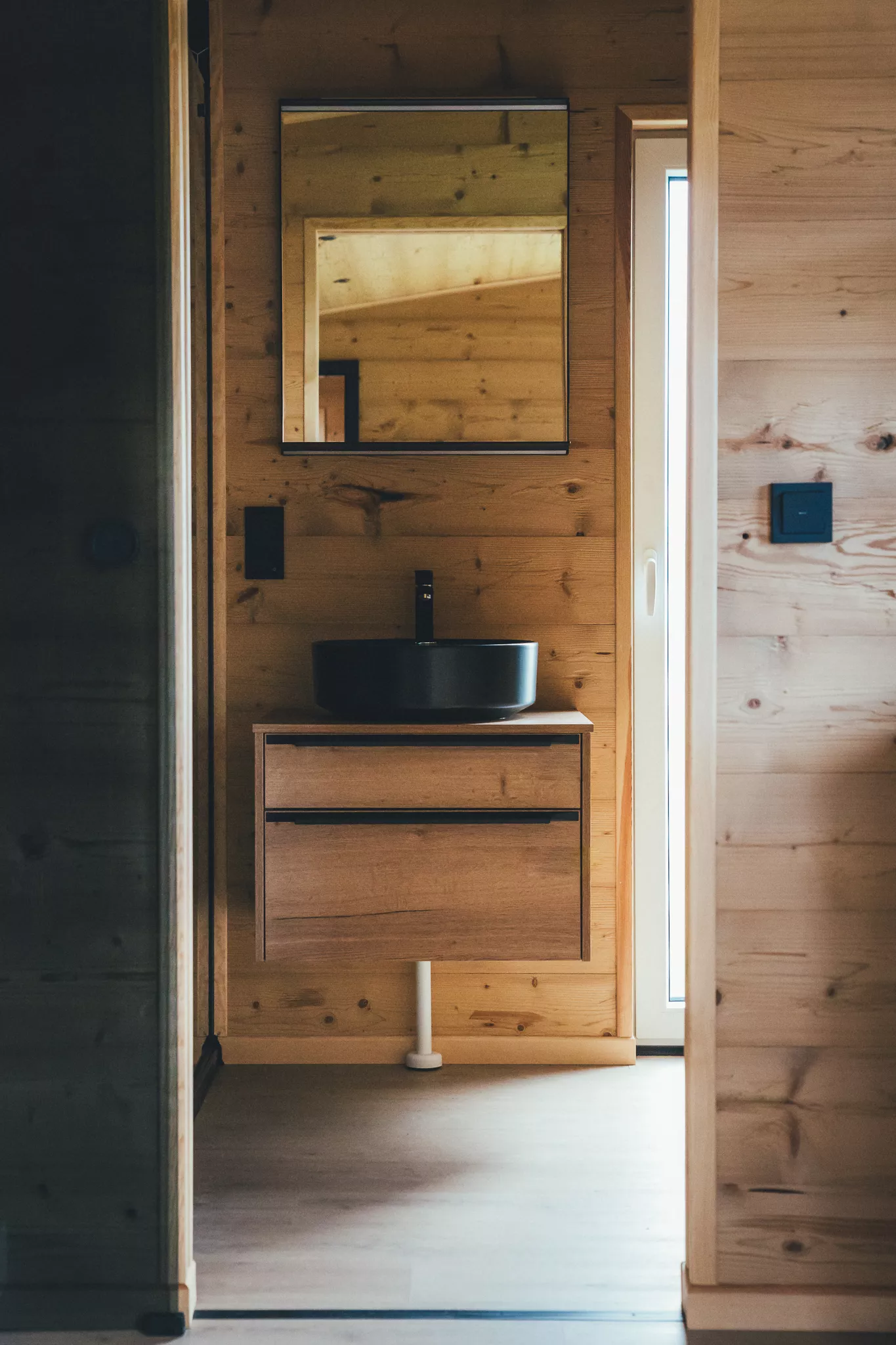 Modernes Bad im Tiny House mit Waschbecken, Spiegel und Holzverkleidung