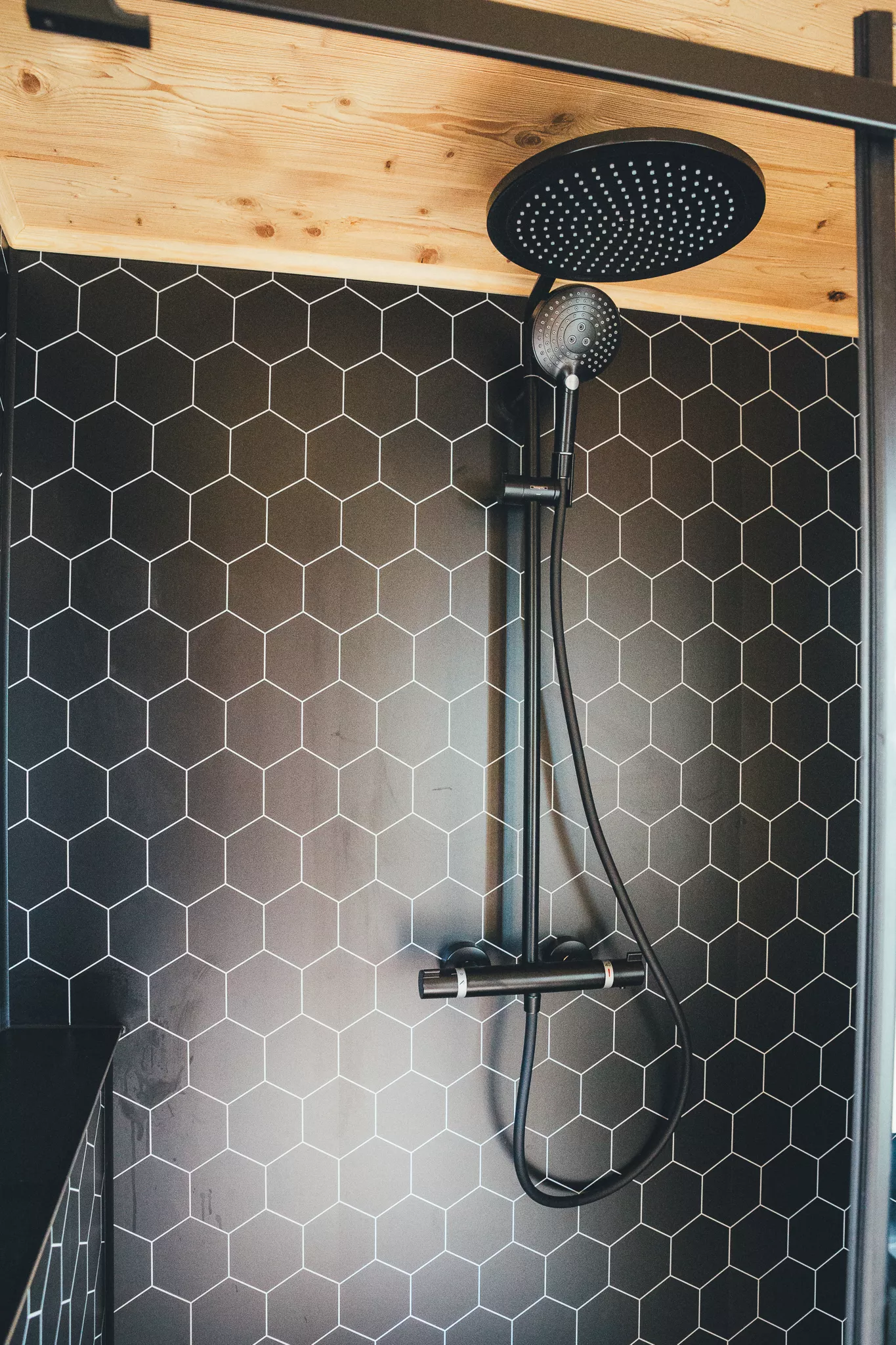 Moderne Dusche mit schwarzer Armatur und hexagonalen Fliesen im Tiny House