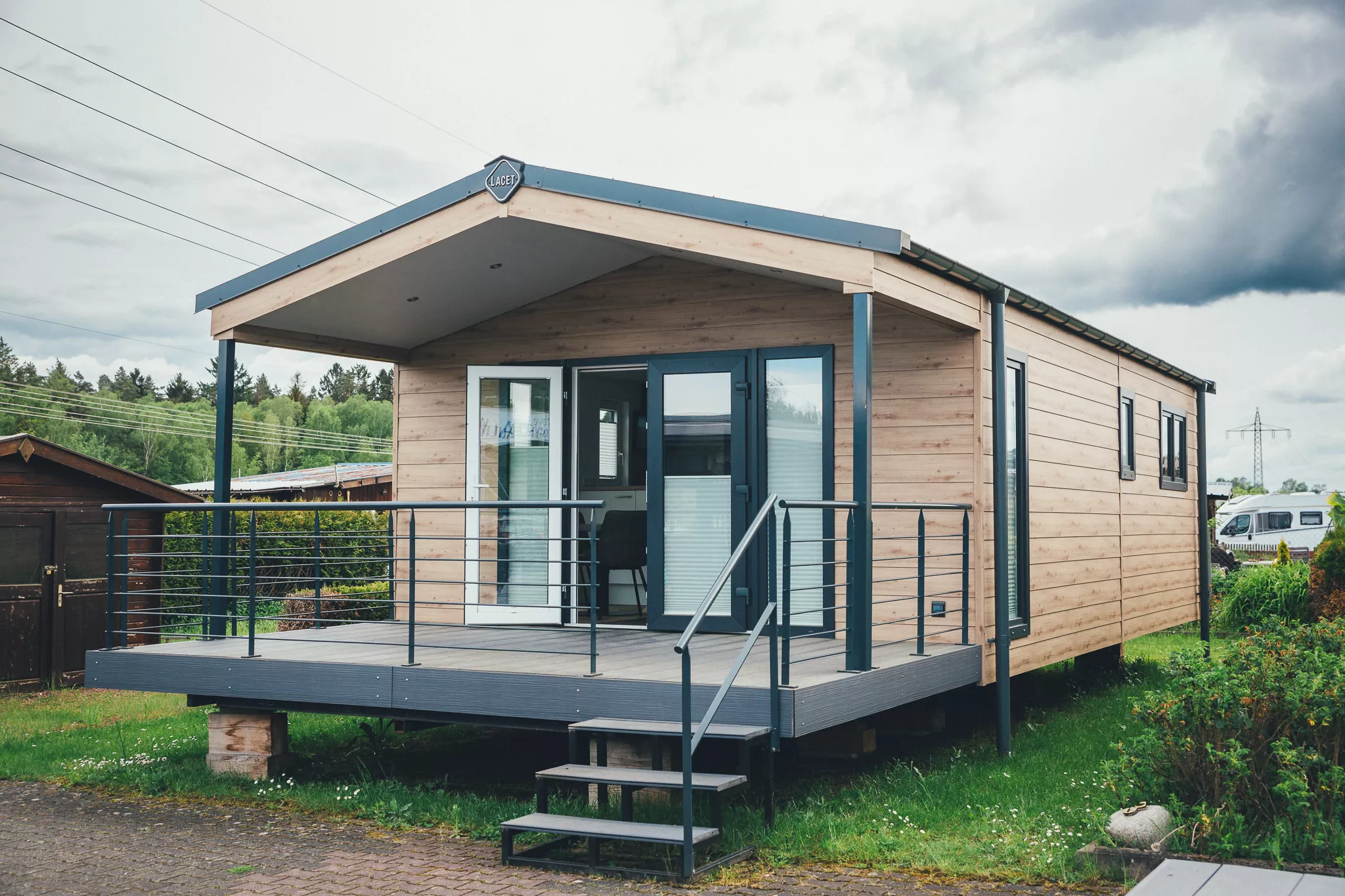 Modernes Tiny House mit Holzfassade, Terrasse und Treppe im Grünen