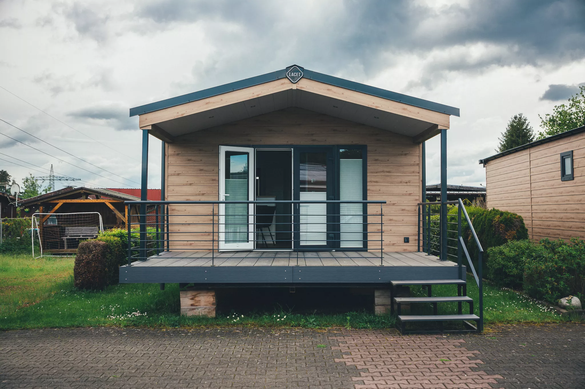 Frontansicht eines Tiny Houses mit Terrasse, Geländer und Treppe