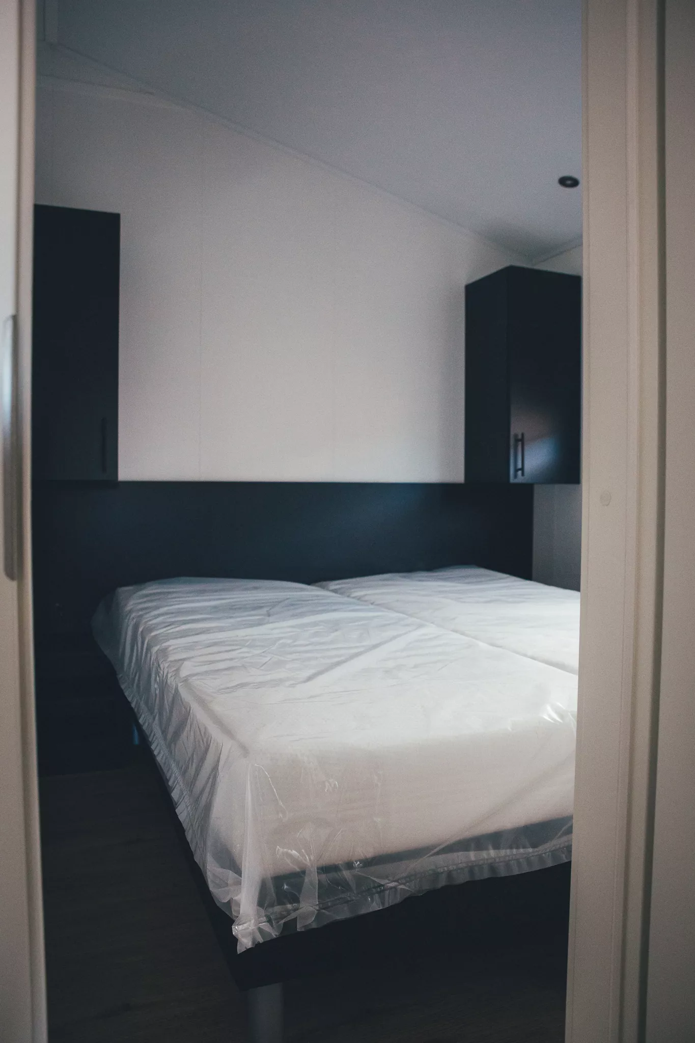 Schlafzimmer im Tiny House mit Doppelbett und schlichten Einbauschränken