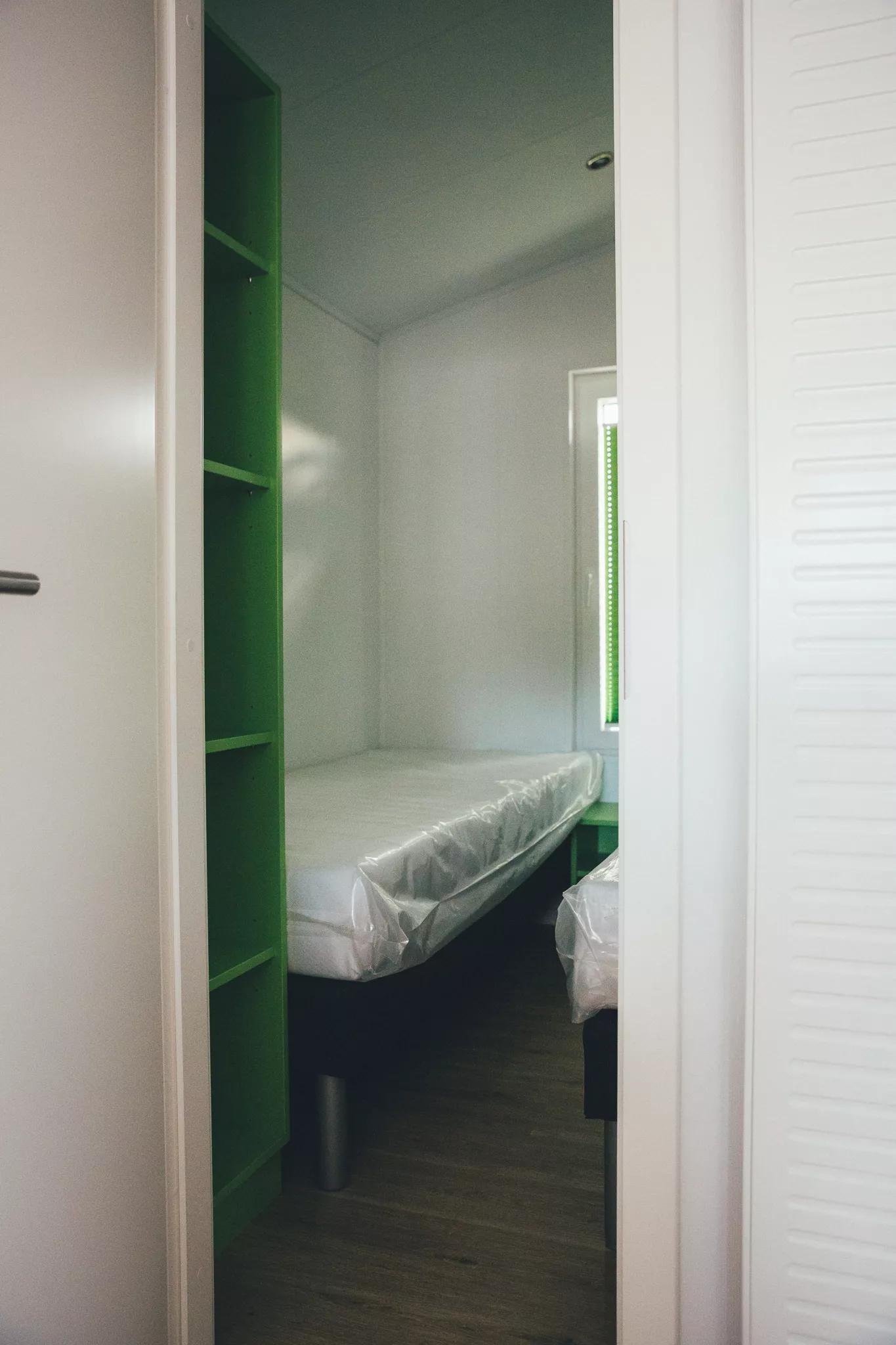 Kleines Schlafzimmer mit Einzelbett, Regal und Fenster im Tiny House