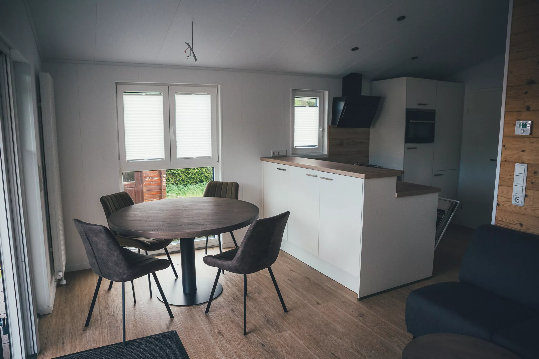 Wohnbereich mit Esstisch, Stühlen und offener Küche im Tiny House