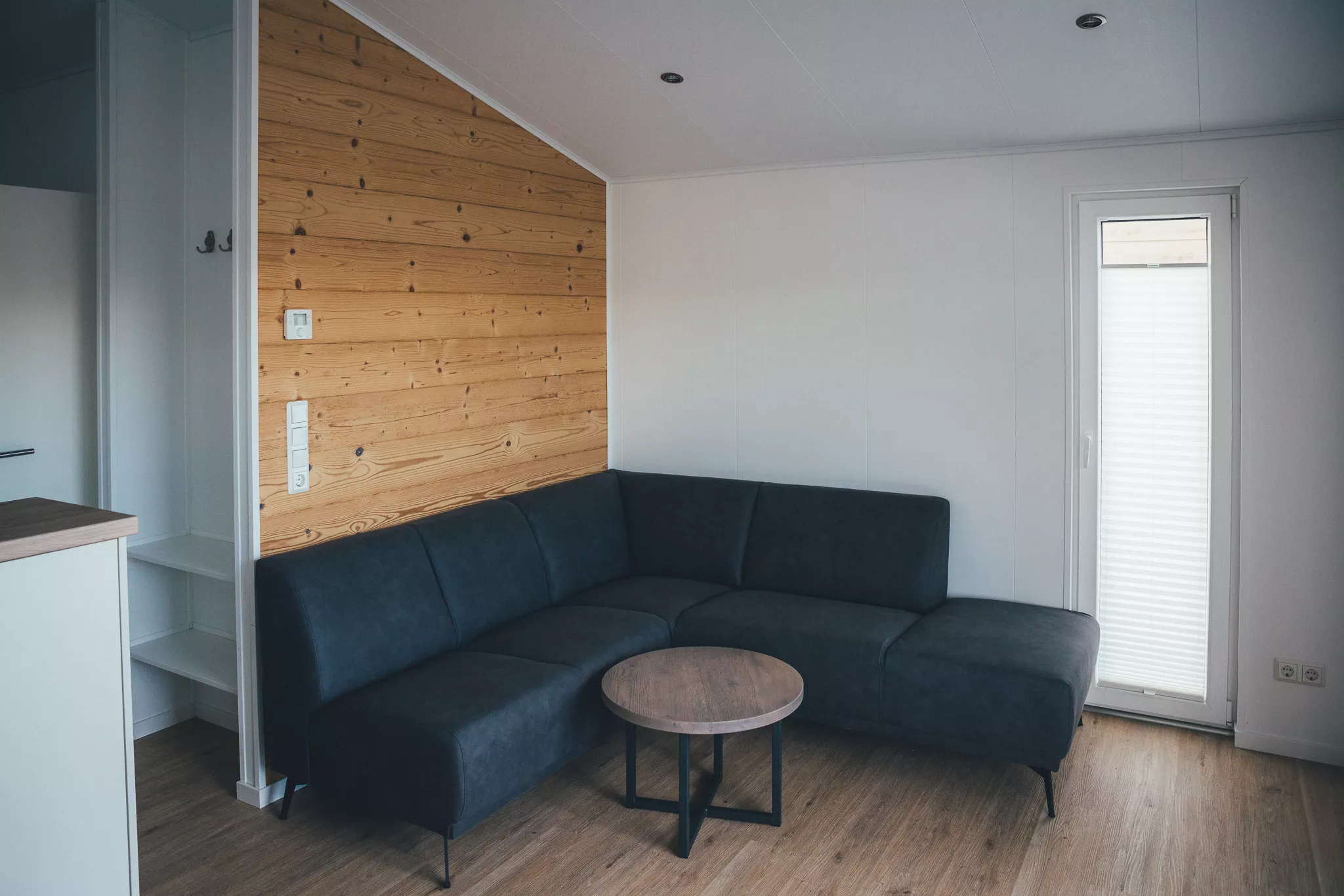 Wohnbereich mit Ecksofa, Couchtisch und Holzverkleidung im Tiny House