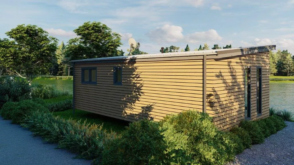 Seitenansicht des Tinyhauses mit Holzverkleidung, Fenster und Blick auf einen See im Hintergrund