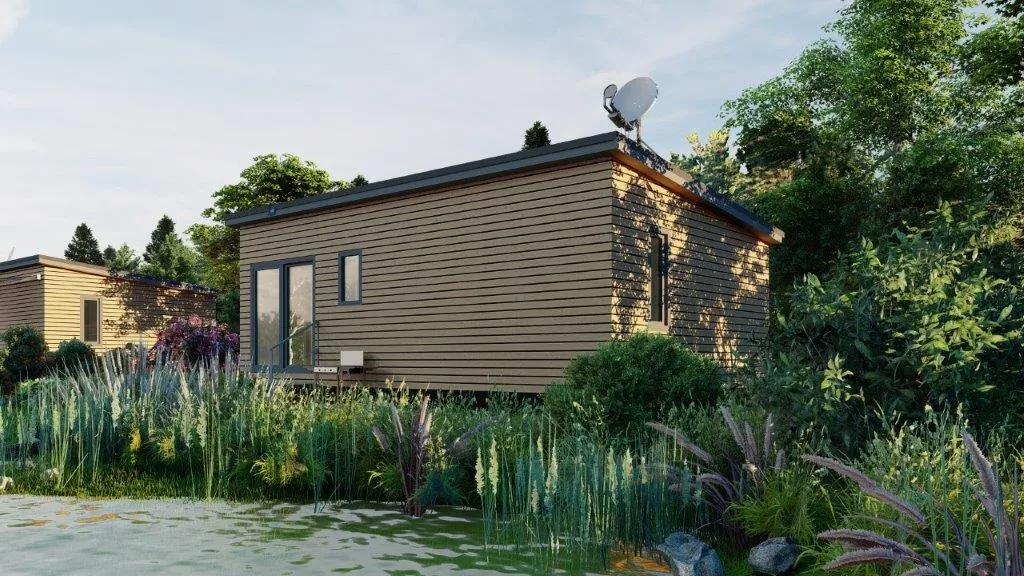 Rückansicht eines Tiny Houses mit dichter Bepflanzung und Wasserlauf im Vordergrund.